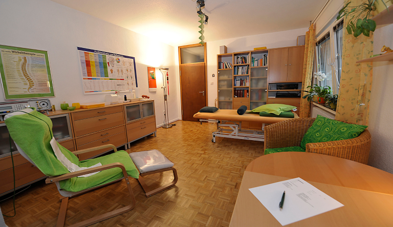 Behandlungsraum der Naturheilpraxis Karin Kossek in Duisburg Rumeln mit Behandlungsliege und grünem Relaxsessel